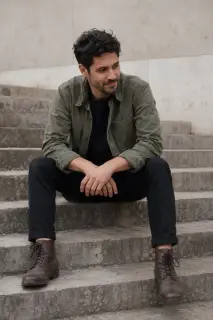 Man seated on stone steps leaning forward with hands clasped